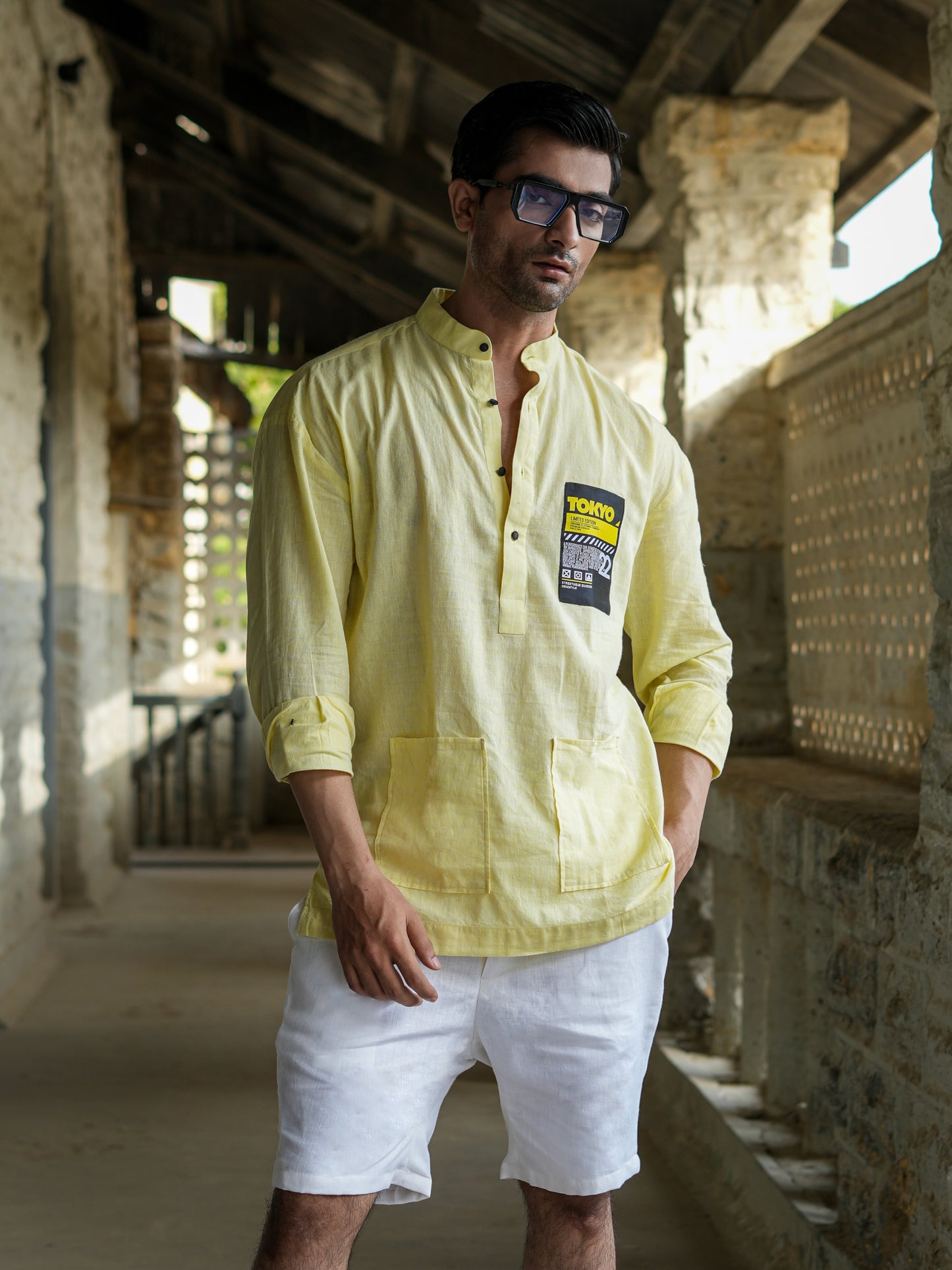 Man wearing a light yellow shirt with a brand logo in an outdoor setting